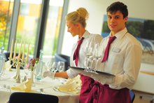 Mitarbeitende des Hotels Franz decken eine Tafel für eine Familienfeier ein.