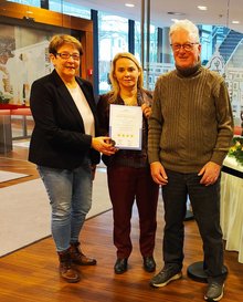 Hoteldirektorin Karin Poppinga zeigt gemeinsam mit 2 Prüfern die Zertifizierungs-Urkunde
